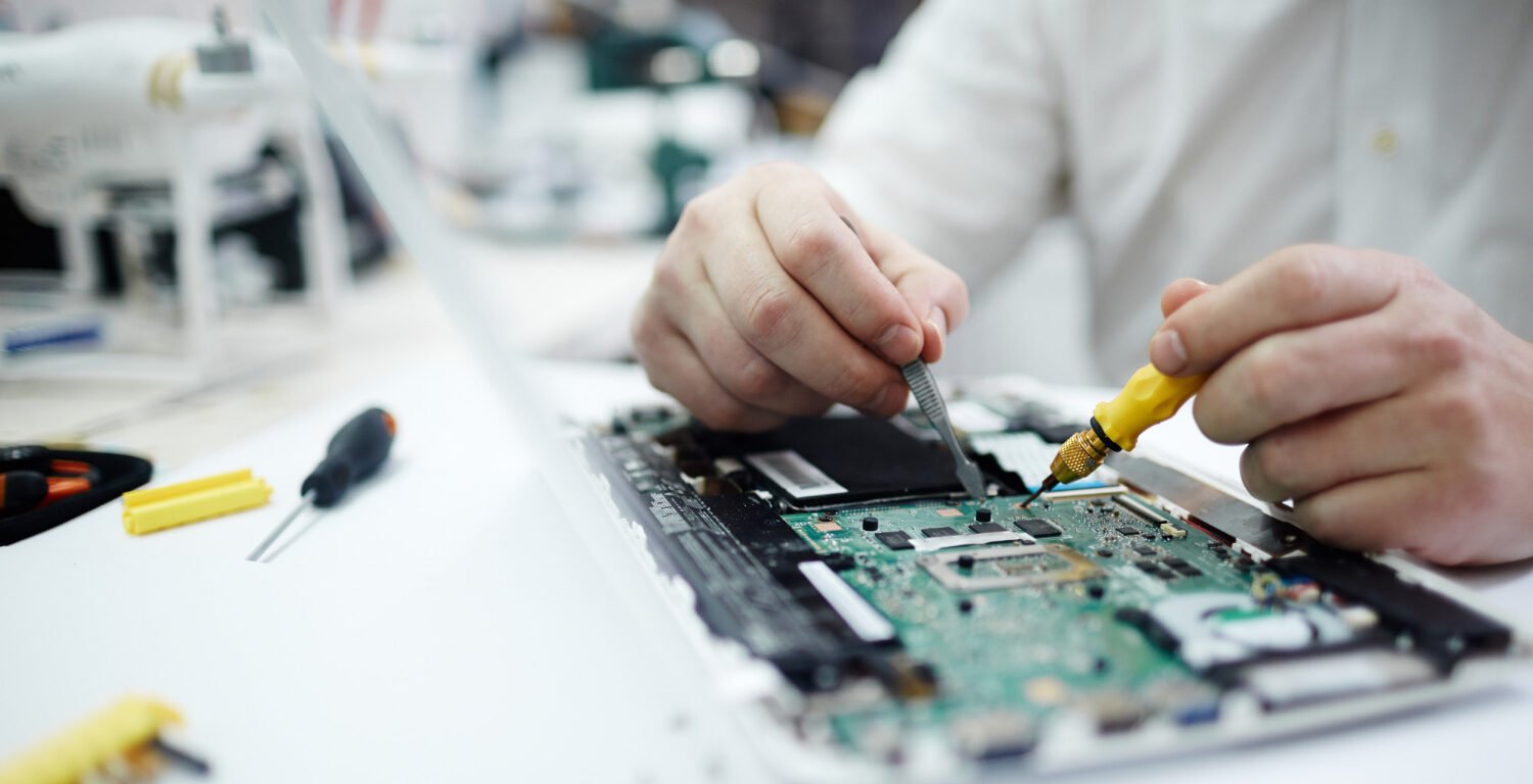 man repairing the circuit board of a laptop