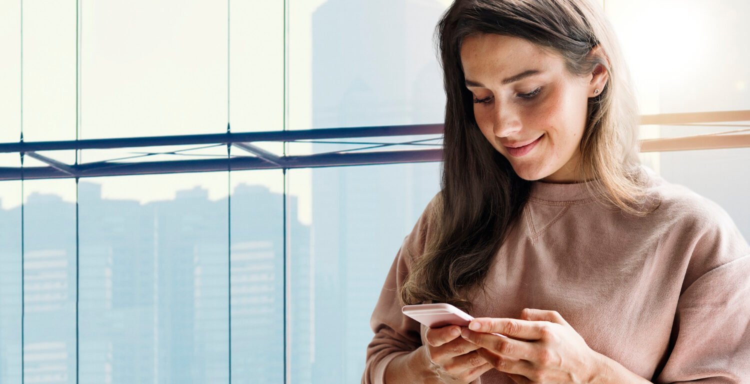 Smiling woman looking at her smartphone in her hand.